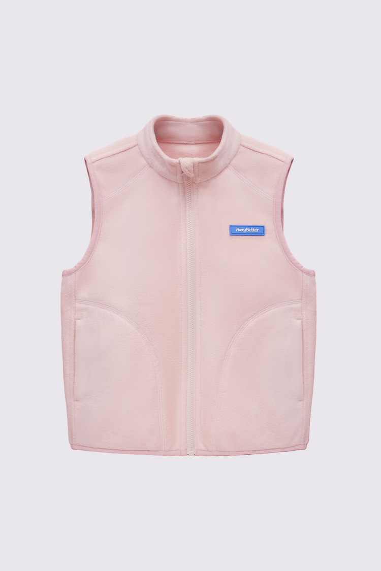 A girl wearing a pink soft lightweight vest with a logo in a snowy landscape