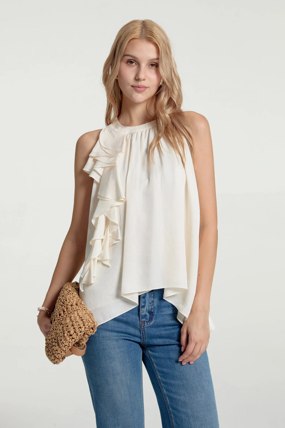 Asymmetrical ruffle halter top styled with blue jeans and a handbag, front view on grey background