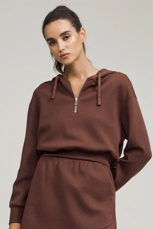 Cropped half-zip fleece hoodie in chestnut brown styled with a matching skirt, front view