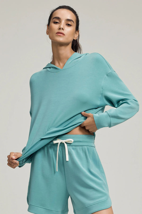 Front view of a seafoam blue Tencel™ hoodie highlighting the crossover hem and relaxed fit