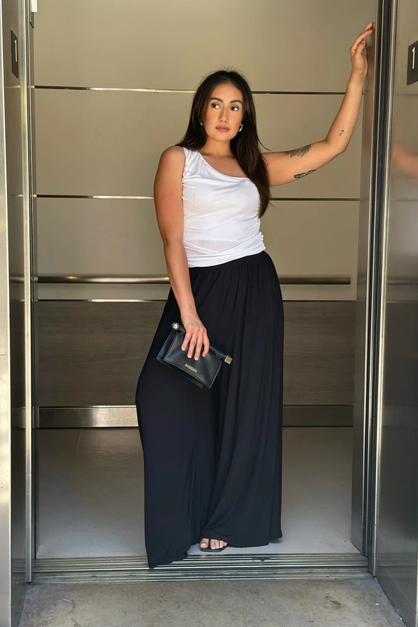 Fluid wide-leg trousers styled with a white tank in an urban setting, front view