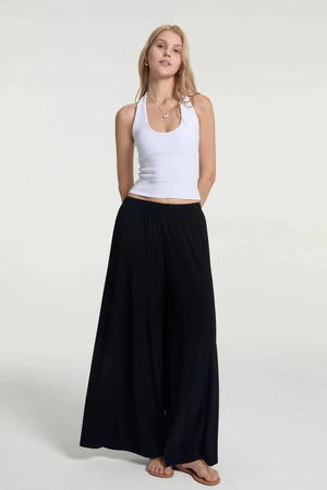 Fluid wide-leg trousers styled with a white tank, front view with a silky, lightweight drape