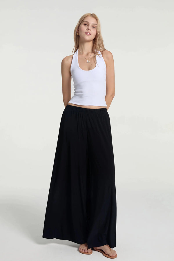 Fluid wide-leg trousers styled with a white tank, front view with a silky, lightweight drape