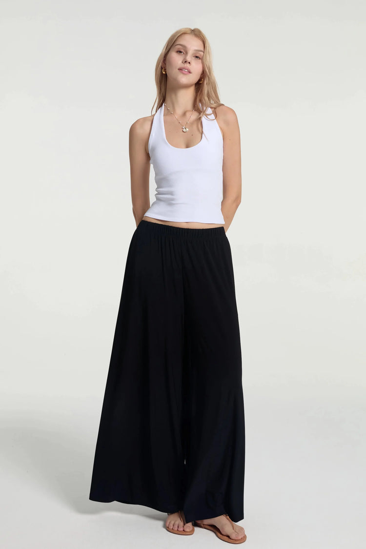 Fluid wide-leg trousers styled with a white tank, front view with a silky, lightweight drape