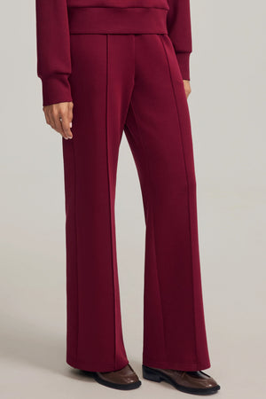 Luxe flare pants in Burgundy Wine styled with a matching sweatshirt, side view on grey background