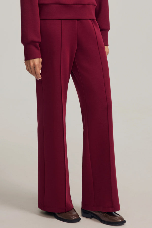 Luxe flare pants in Burgundy Wine styled with a matching sweatshirt, side view on grey background