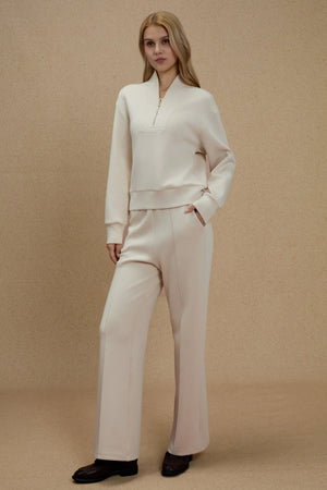Luxe flare pants in oatmilk beige styled with a matching top on a warm neutral background