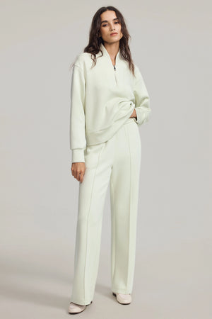 Pistachio cream luxe flare pants styled with a matching sweatshirt, front view on grey background