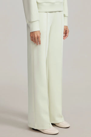 Side view of cream green wool-blend flare pants with a smooth, fluid drape