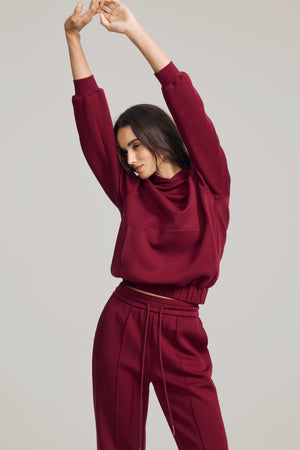 Women’s burgundy wine fleece hoodie worn in motion, highlighting soft comfort and ease