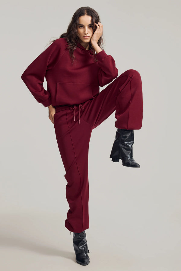 Burgundy wool-blend joggers showing a smooth, cozy fabric with fluid movement