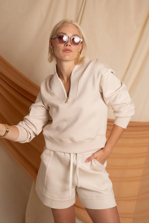Oatmilk Beige half-zip pullover styled with matching shorts for a relaxed, modern look