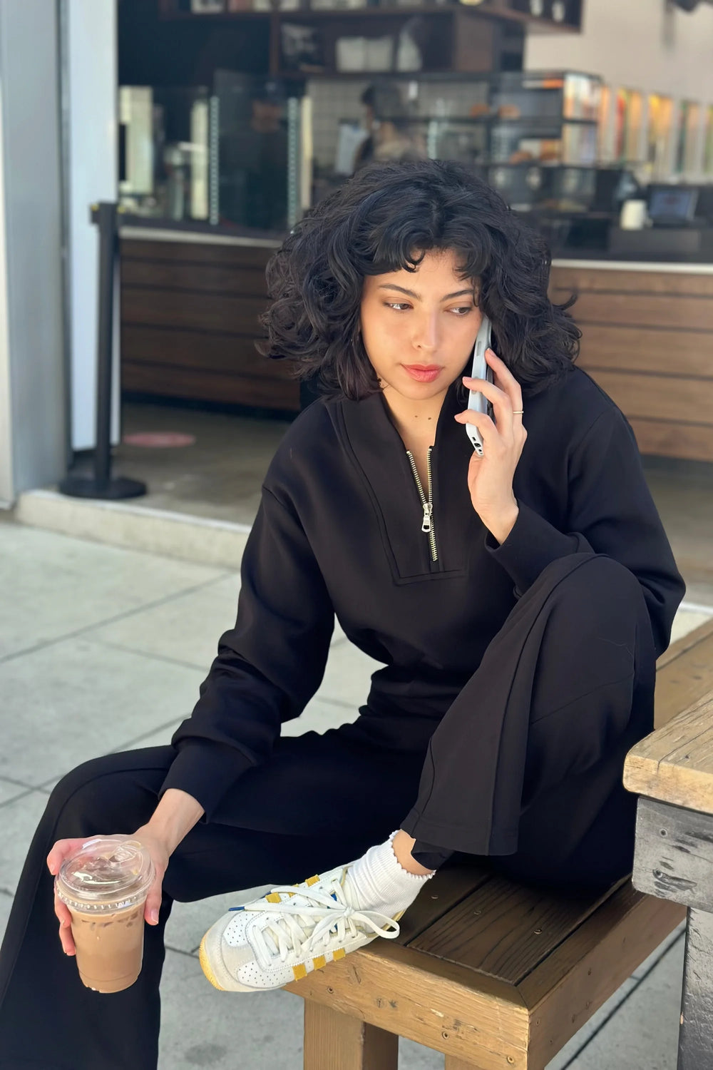 Luxe half-zip pullover in Onyx Black styled with matching trousers in an outdoor café setting