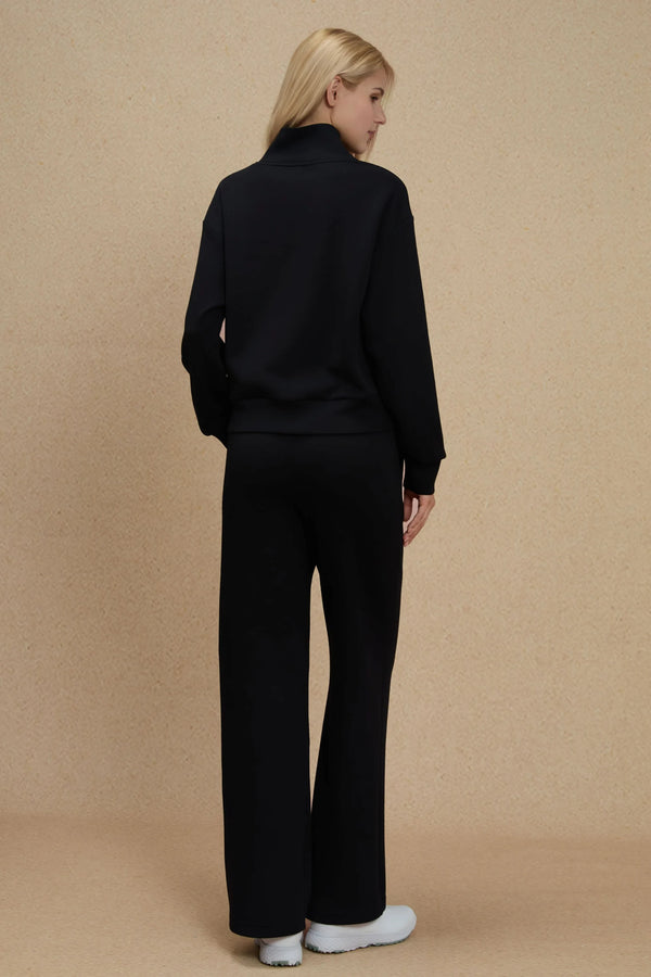 Back view of a black half-zip pullover styled with matching pants, showing a clean silhouette