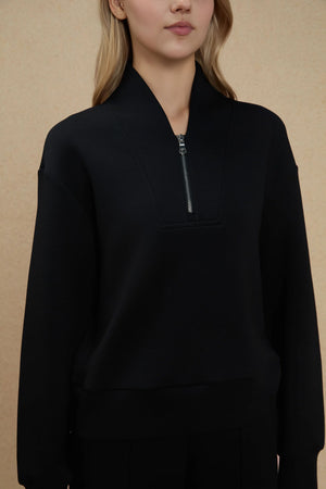 Close-up of the half-zip neckline showing refined detailing and soft double-faced texture