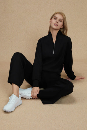 Luxe half-zip pullover in Onyx Black worn in a seated pose, emphasizing relaxed refinement
