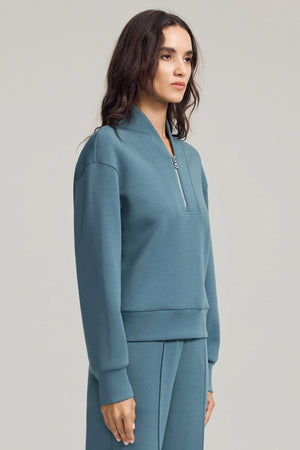 Side view of a wool-blend half-zip pullover with fluid structure and clean lines