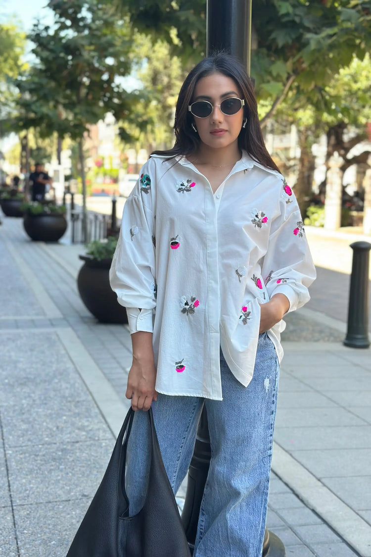 Embroidered oversized button-down shirt styled with blue jeans in a modern street setting