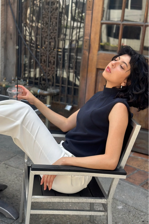 Sculpted sleeveless performance top styled with white trousers in an outdoor café setting