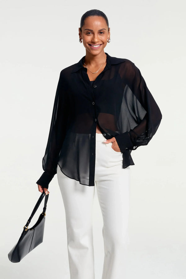 Sheer black silk oversized button-down shirt styled with white trousers, front view
