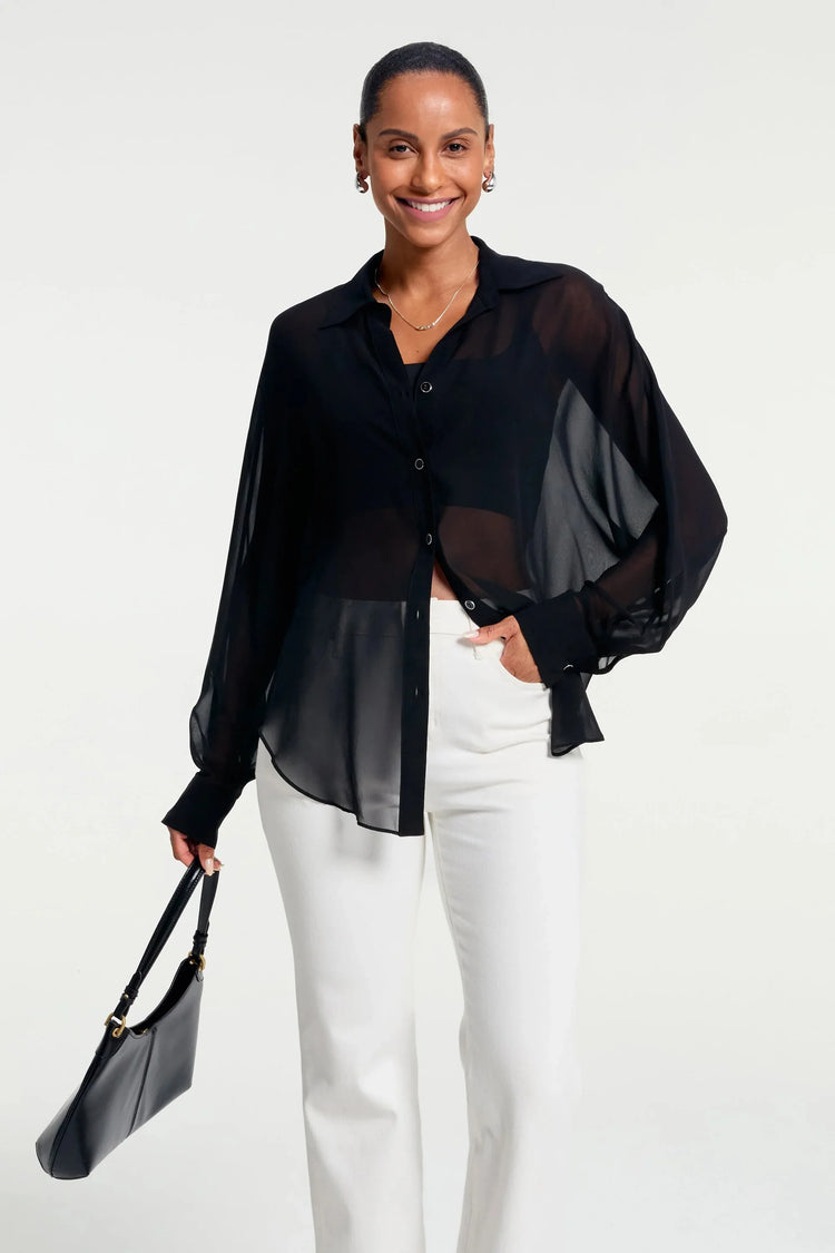 Sheer black silk oversized button-down shirt styled with white trousers, front view
