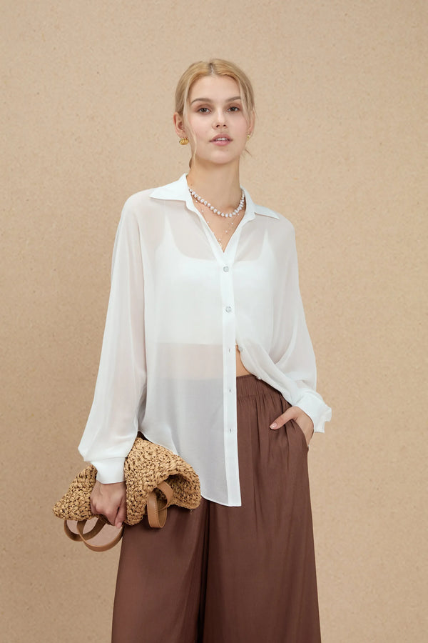 Sheer white silk oversized button-down shirt styled with brown wide-leg trousers, front view