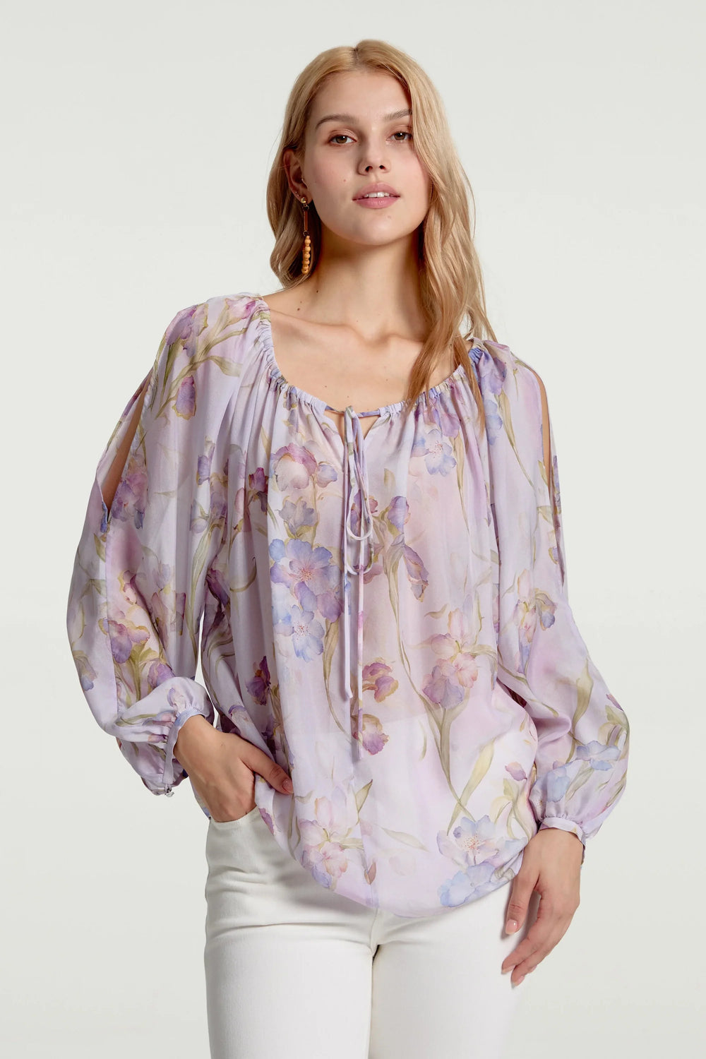 Sheer silk peasant blouse with soft lavender florals styled with white trousers, front view on grey background