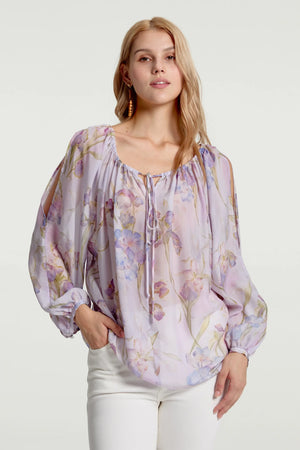 Sheer silk peasant blouse with soft lavender florals styled with white trousers, front view on grey background