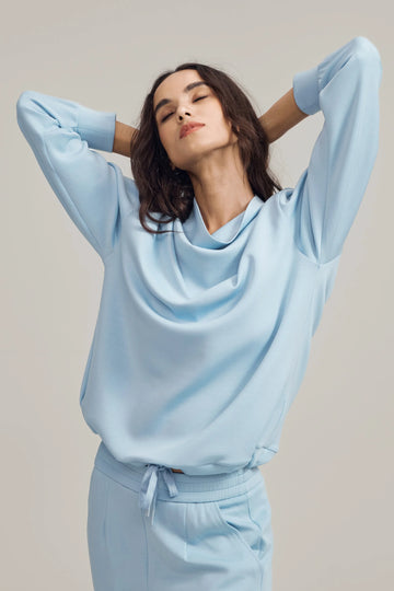Soft drape funnel-neck pullover in Powder Blue styled with matching sweatpants, front view on grey background