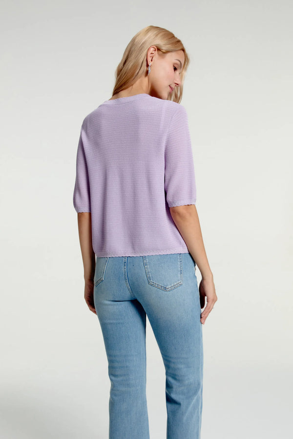 Back half-body view of women’s soft knit hook-front cardigan styled with blue jeans