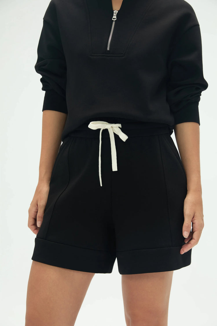 Close-up front view of black structured lounge shorts highlighting the clean cuffed hem