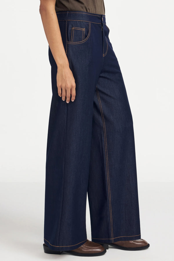 Side view of ink rinse wide-leg denim highlighting an elongated, structured silhouette