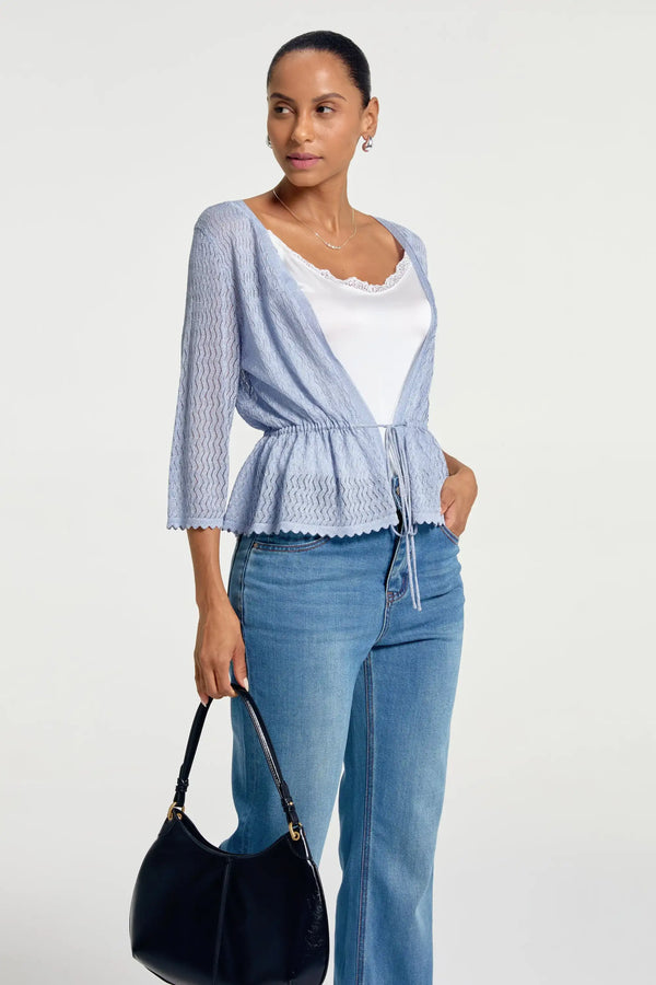 Women’s soft blue textured peplum tie-front cardigan styled with blue jeans and a black handbag, upper-body front view