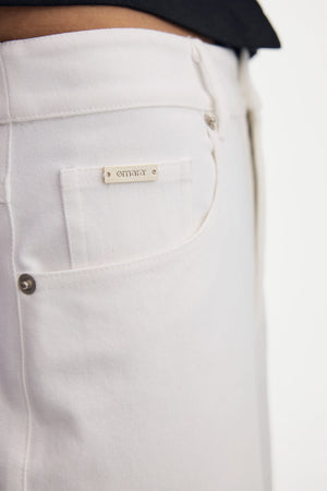 Detail view of the front pocket design on high-rise white denim jeans