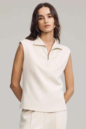 Modern zip-collar sleeveless pullover in cream sandshell styled with matching pants, front view on grey background