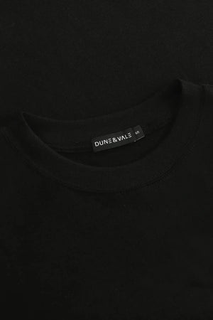 Close-up of the crewneck collar on a men’s jet black linen–Supima tee.