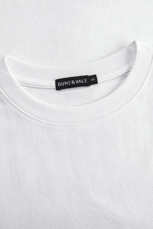 Close-up of the crewneck collar on a men’s pure white linen–Supima tee.