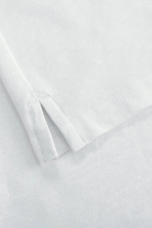 Detail of the subtle side slit at the hem of a men’s alpine white linen–Supima button-neck henley.