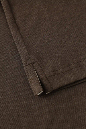 Detail of the subtle side slit at the hem of a men’s espresso linen–Supima button-neck henley.