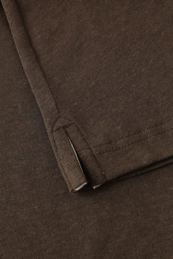 Detail of the subtle side slit at the hem of a men’s espresso linen–Supima button-neck henley.