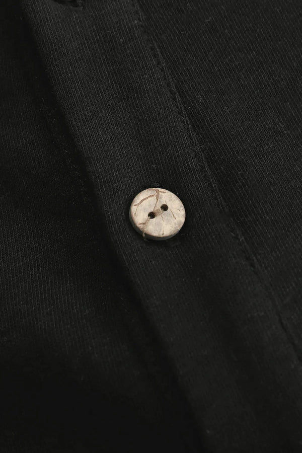 Detail view of the button closure on a men’s onyx black linen–Supima button-neck henley.