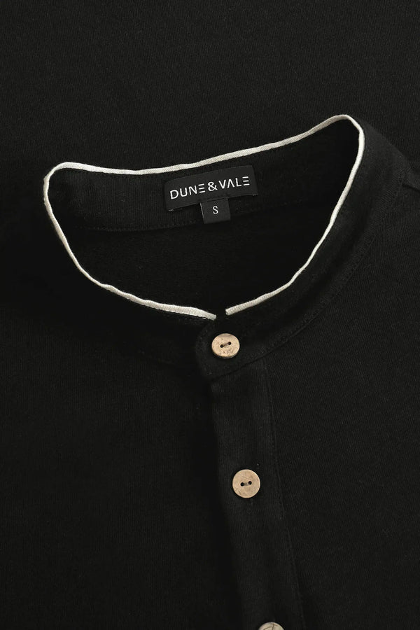 Close-up of the button-neck mandarin collar on a men’s onyx black linen–Supima henley.