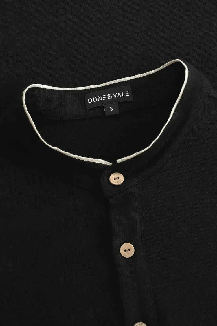 Close-up of the button-neck mandarin collar on a men’s onyx black linen–Supima henley.