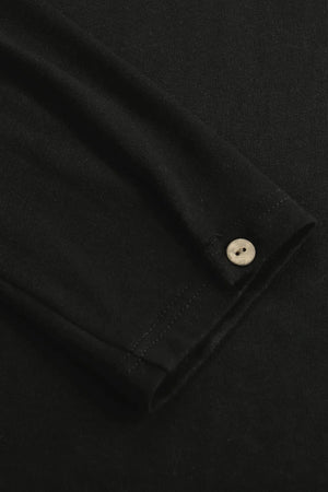 Close-up of the single-button cuff on a men’s onyx black linen–Supima henley, designed for clean everyday ease.