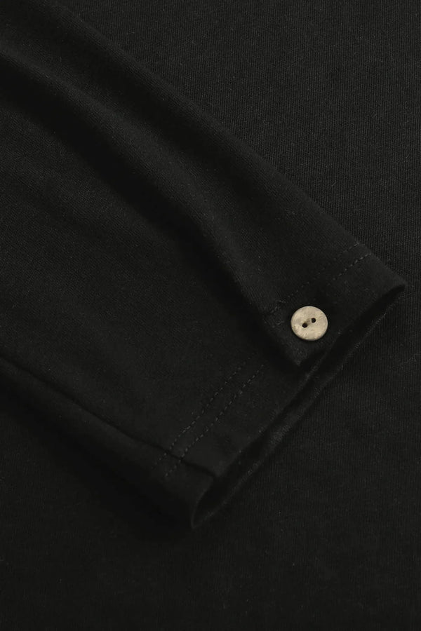 Close-up of the single-button cuff on a men’s onyx black linen–Supima henley, designed for clean everyday ease.