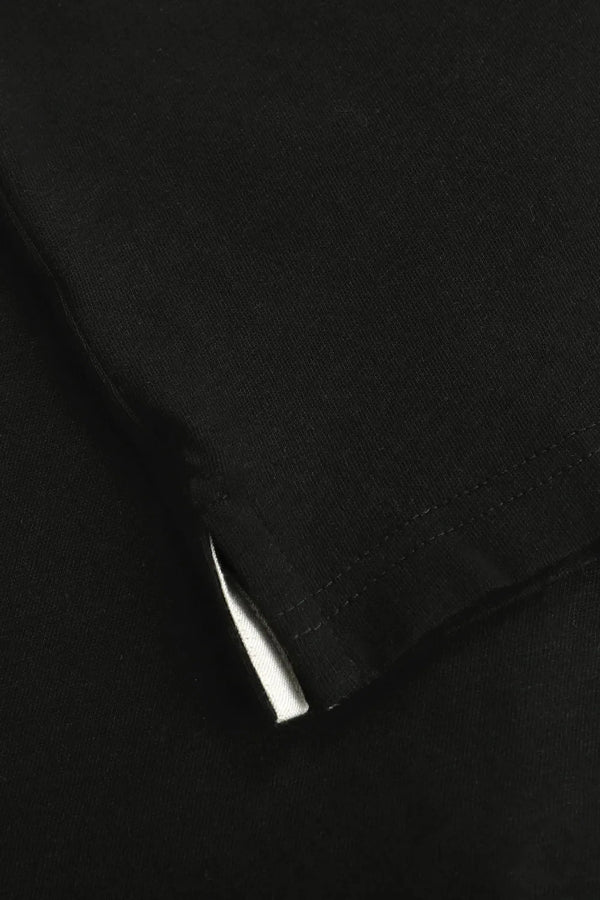 Detail of the subtle side slit at the hem of a men’s onyx black linen–Supima button-neck henley.
