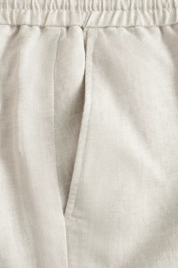 Detail view of the front pocket on men’s driftwood beige linen-Tencel drawstring trousers.