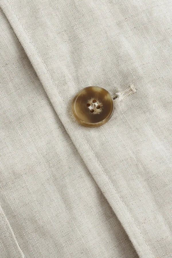 Close-up of the button closure on a men’s driftwood beige linen-Tencel safari jacket.