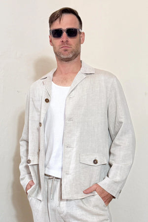 Front view of a men’s driftwood beige linen-Tencel safari jacket styled with matching trousers for a clean, warm-weather look.