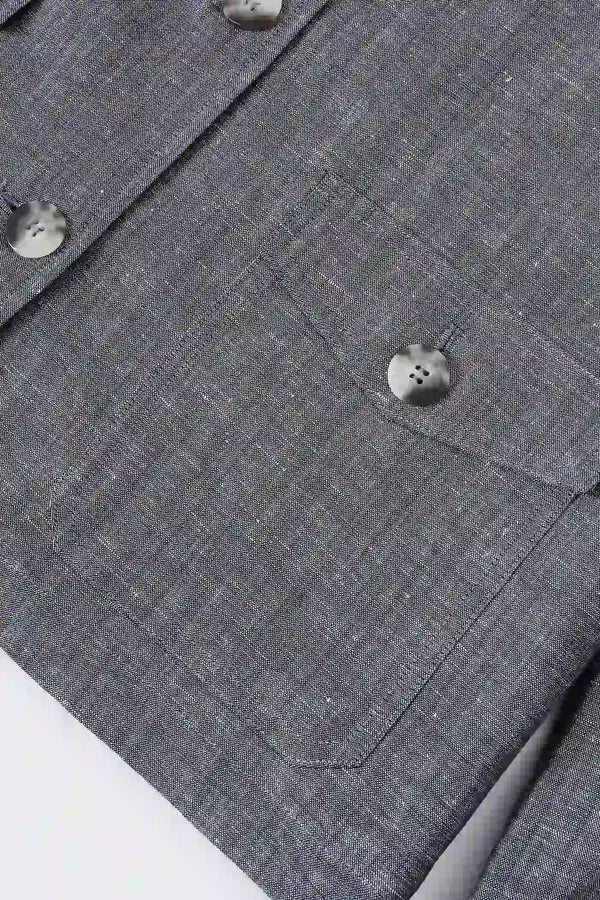 Close-up of the hem finish on a men’s heather grey linen-Tencel safari jacket, showing clean construction.
